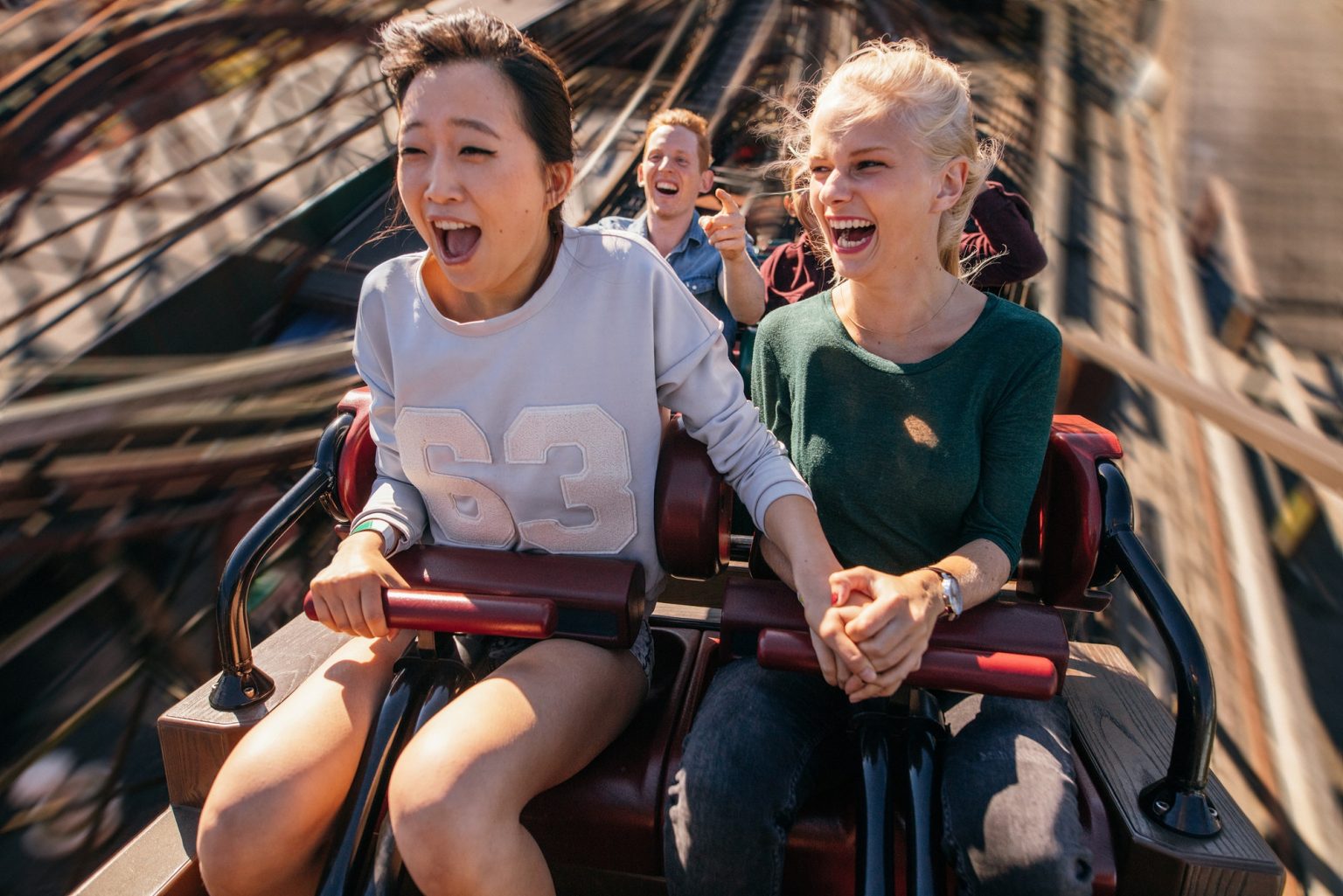 Happy young people riding a roller coaster