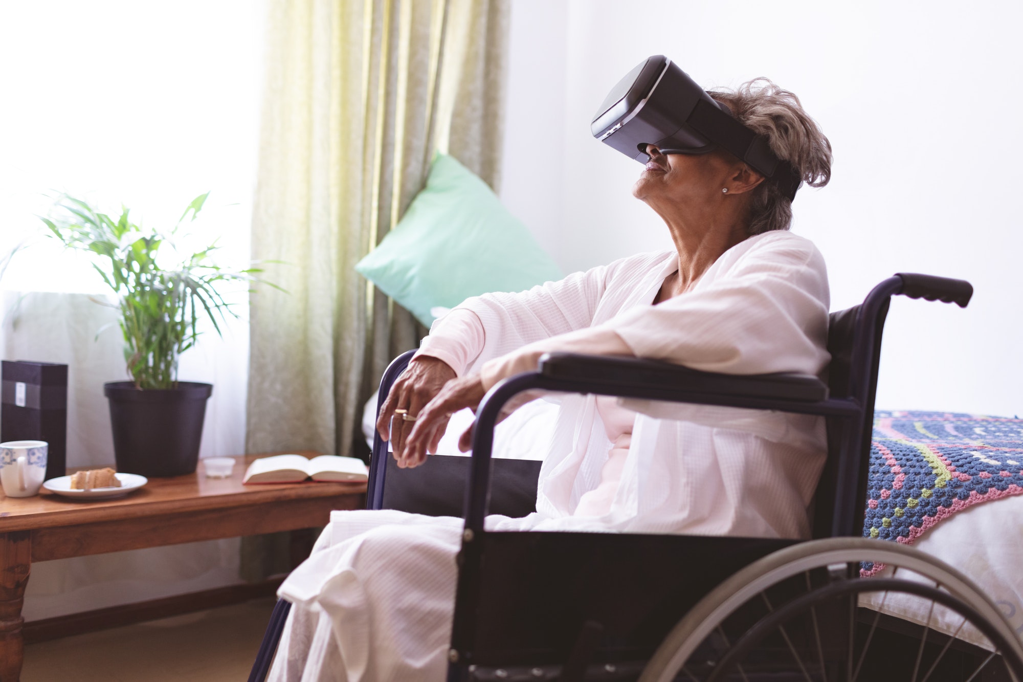 Side view of senior mixed race woman using virtual realty headset at nursing home