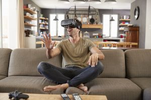 Man Sitting On Sofa Wearing Virtual Reality Headset