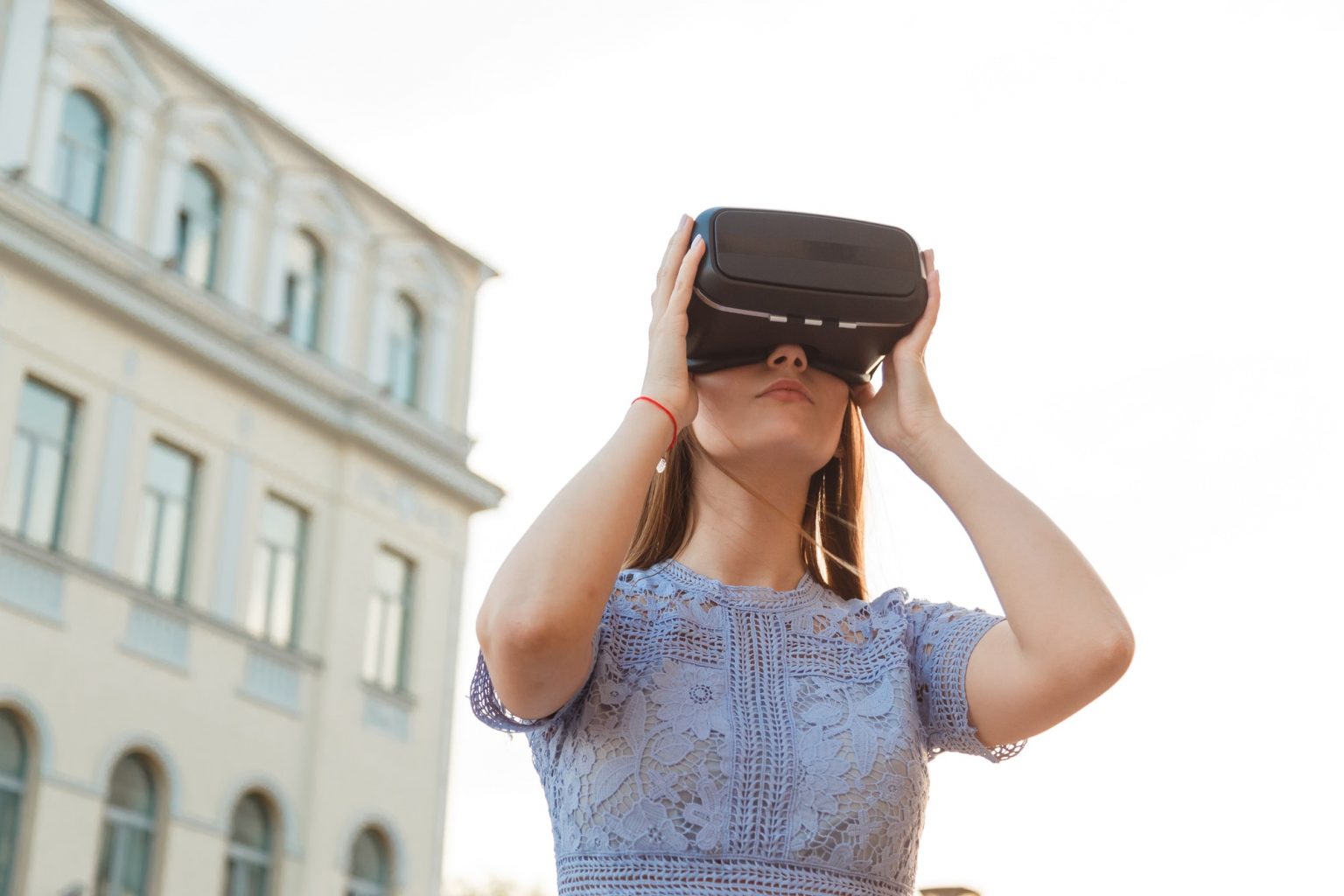 Young brunette is amused by her first encounter with futurist virtual reality glasses